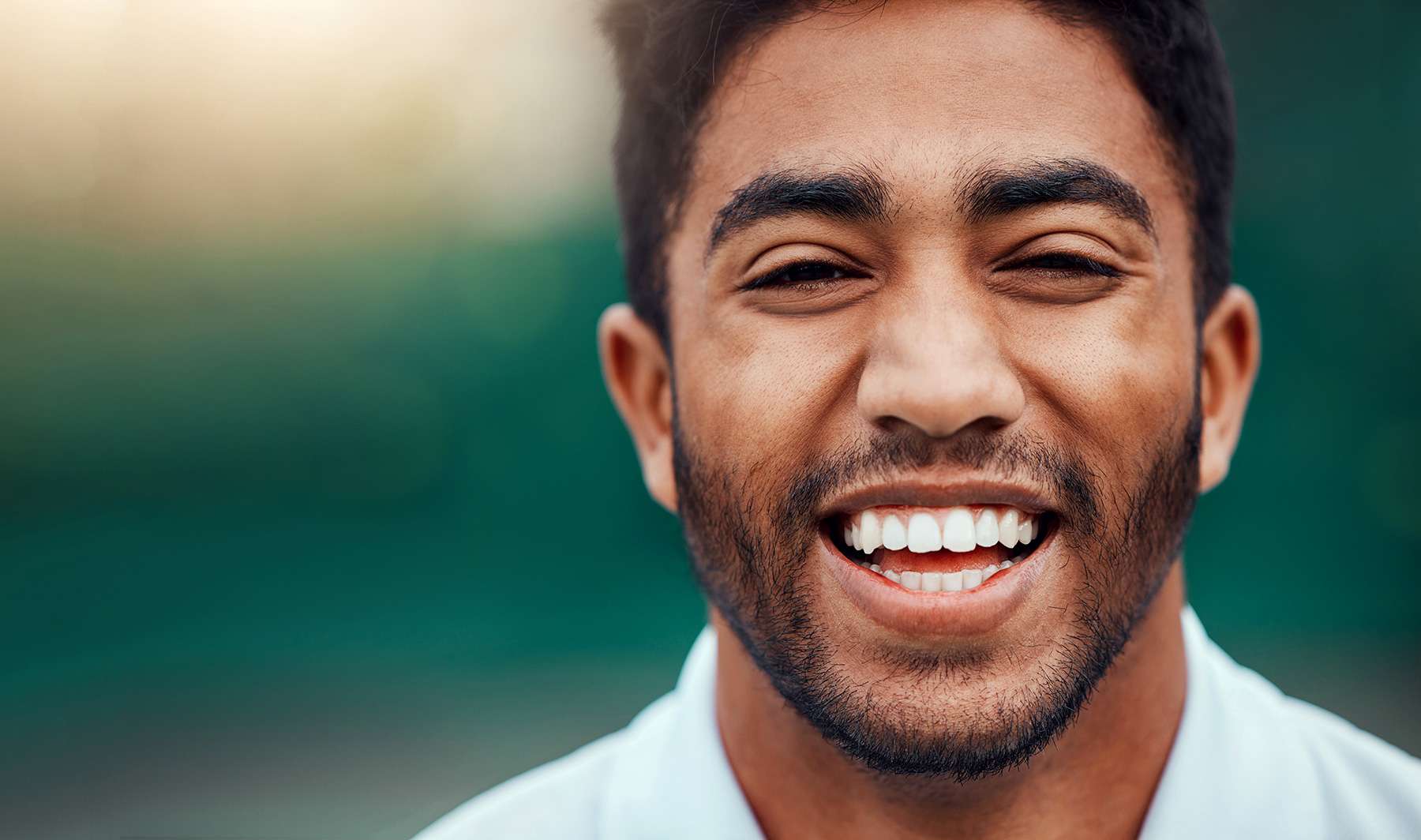 A person widely smiling directly at the camera for a blog on the Benefits of Minimally Invasive Surgery in Miami